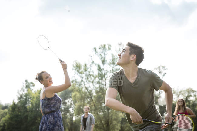 Grupo de jovens adultos jogando badminton no campo — Fotografia de Stock