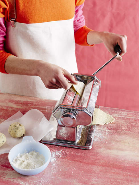 Imagen recortada de la mujer preparando galletas de agua con máquina de pasta - foto de stock