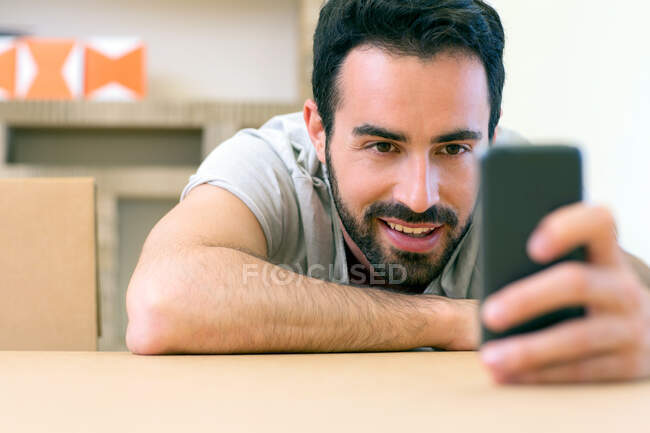 Young male designer reading smartphone texts at boardroom table — Stock Photo