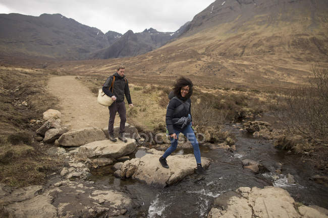 Женщина, пересекающая ручей, Бассейны Феи, недалеко от Гленхриттла, остров Скай, Гебриды, Шотландия — стоковое фото