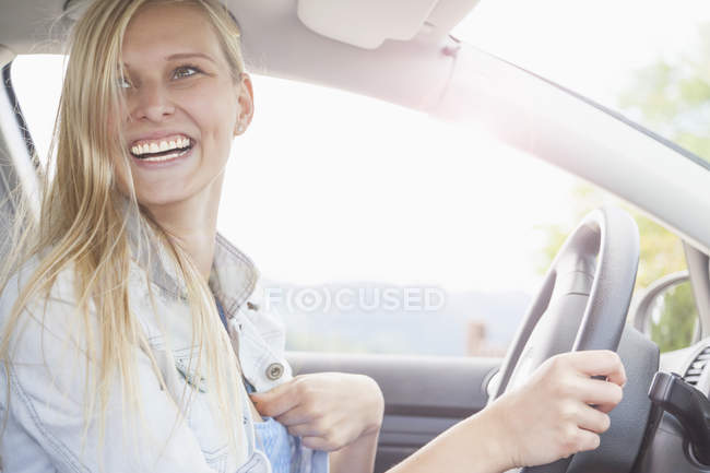 Молодая женщина, улыбающаяся за рулем автомобиля — стоковое фото