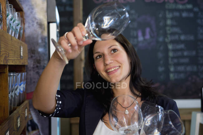 Mulher verificando copos de vinho na loja — Fotografia de Stock