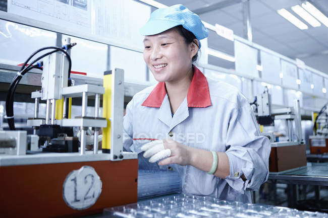 Travailleur féminin utilisant un équipement à l'usine de batteries e-cigarettes, Guangdong, Chine — Photo de stock