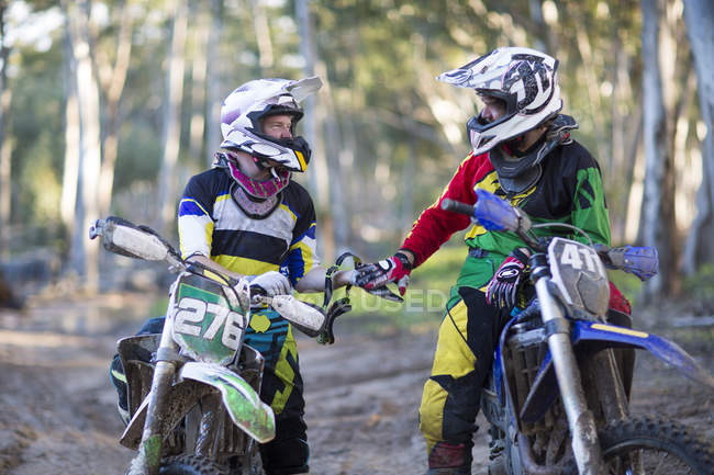 Two young male motocross riders chatting on forest track — Stock Photo