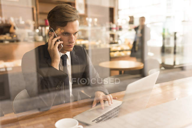 Uomo d'affari che lavora su laptop in caffè — Foto stock
