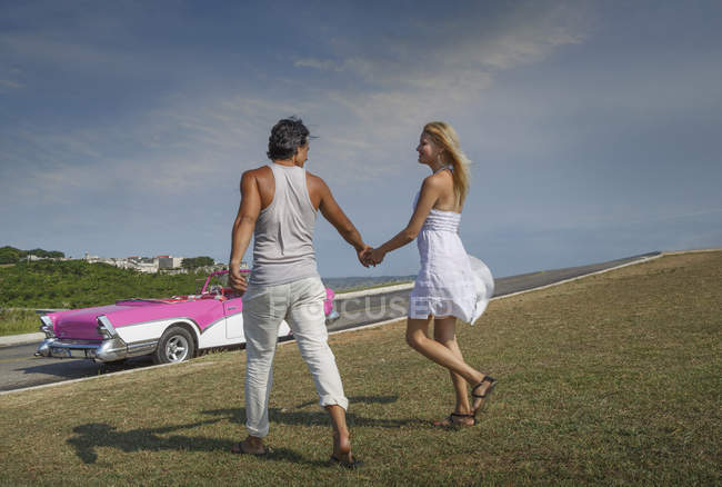 Couple holding hands, Convertible in background — Stock Photo