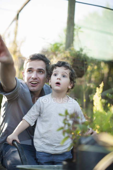 Mid adulto homem e filho olhando surpreso no jardim — Fotografia de Stock