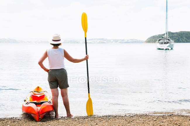 Rear view of senior woman and sea kayak — Stock Photo