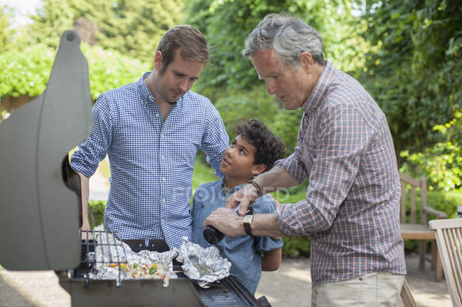 Three generation family cooking on barbecue — Stock Photo