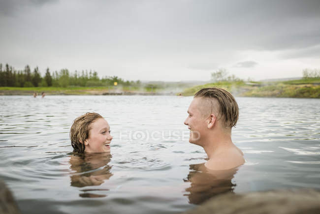 Giovane coppia sorridente che si rilassa nella sorgente termale Secret Lagoon (Gamla Laugin), Fludir, Islanda — Foto stock