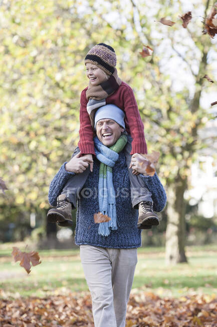 Отец и сын в парке, отец носит сына на плечах, смеется — стоковое фото