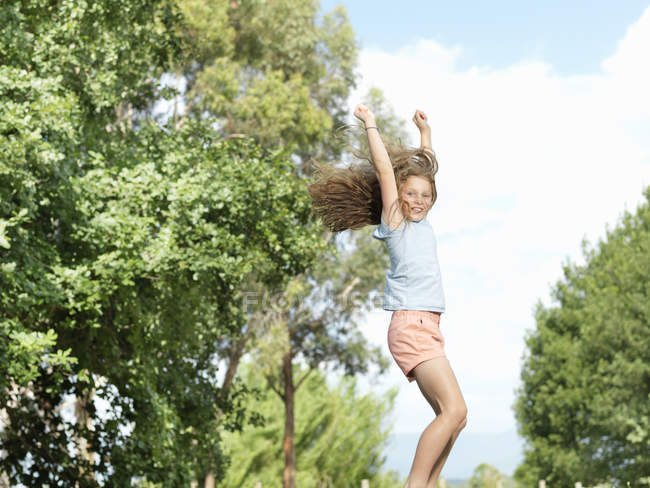 Menina pulando com os braços estendidos, ao ar livre — Fotografia de Stock
