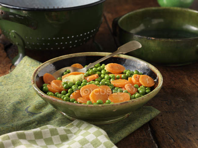 Guisantes y zanahorias en rodajas en el plato - foto de stock