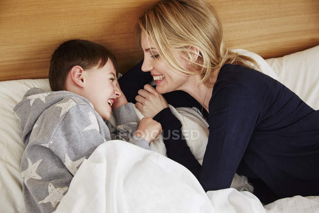 Madre e figlio ridendo a letto — Foto stock