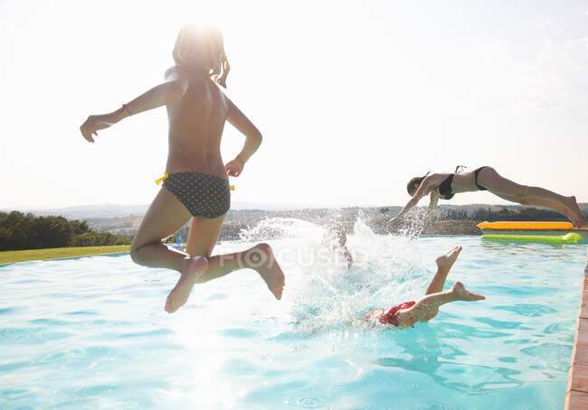 Three people jumping into swimming pool — Stock Photo