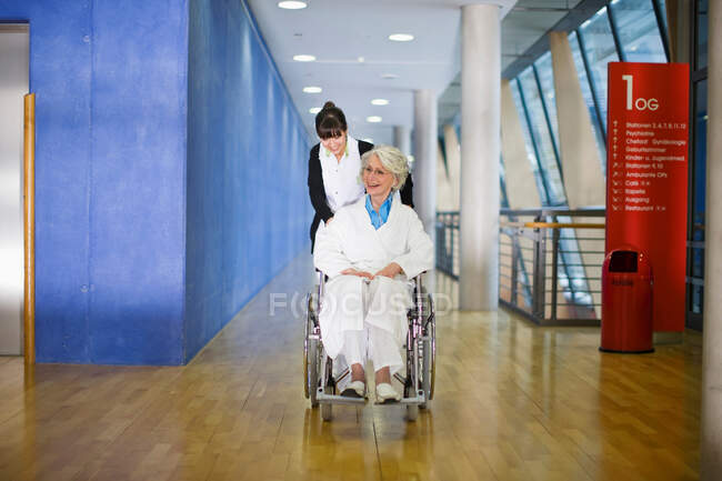 Vieja en silla de ruedas y enfermera - foto de stock