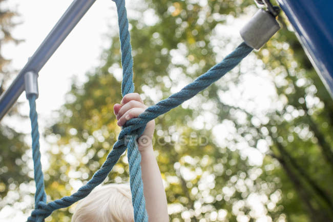 Bébé fille sur le cadre d'escalade au parc, se concentrer sur la main — Photo de stock