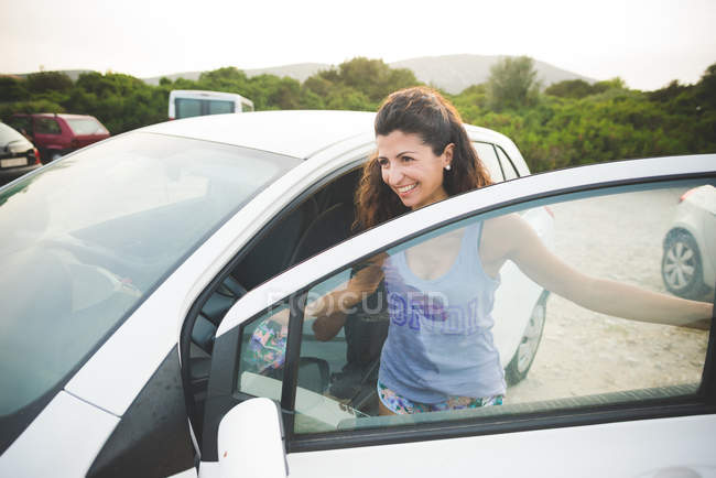Счастливая женщина садится в машину на побережье — стоковое фото