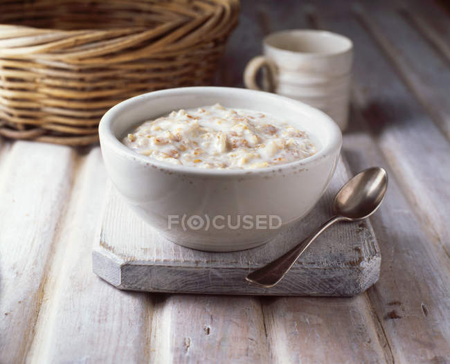 Ciotola di porridge con cucchiaio su tavola di legno — Foto stock