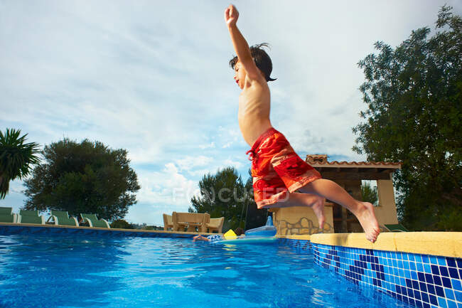 Молодий хлопчик стрибає в басейн — стокове фото