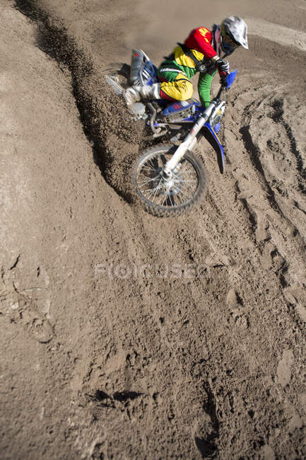 Giovane pilota motocross maschile corse giù collina fango — Foto stock