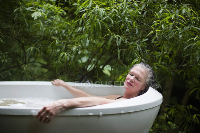 Mulher madura relaxando no banho de espuma de jardim no retiro ecológico — Fotografia de Stock