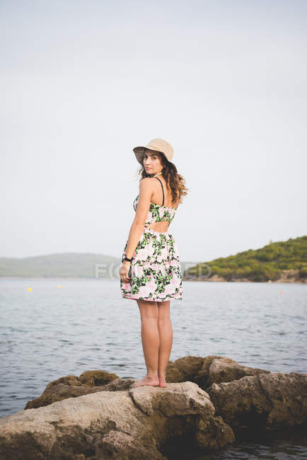 Mulher de pé sobre rochas junto ao mar — Fotografia de Stock