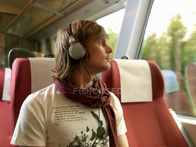 Молодой человек в поезде смотрит в окно — стоковое фото