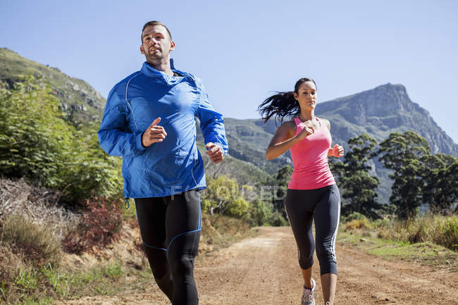 Giovane coppia jogging nella foresta — Foto stock