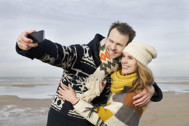 Середині дорослих пара беручи selfie з смартфон на пляжі, Bloemendaal aan Zee, Нідерланди — стокове фото