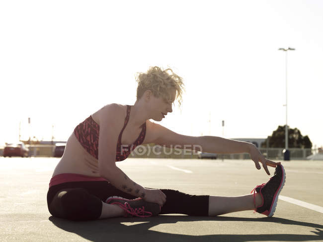 Junge Frau streift sich beim Training auf Parkplatz die Zehen — Stockfoto