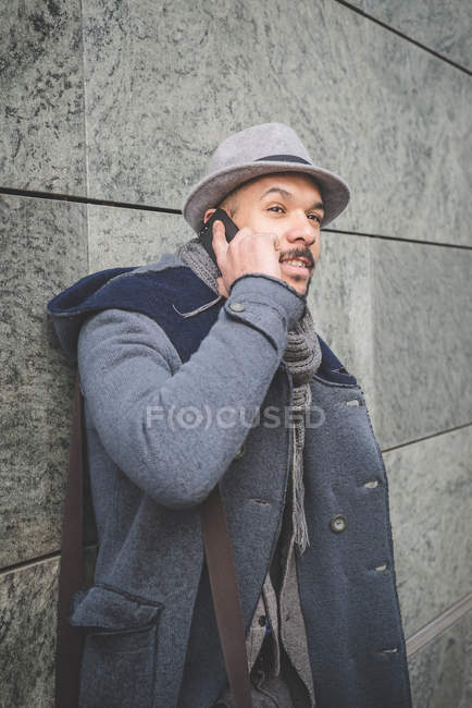 Businessman leaning against wall and talking on smartphone — Stock Photo