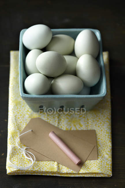 Chicken eggs with chalk and tag on kitchen towel — Stock Photo