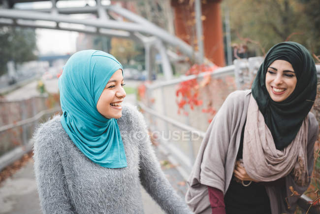 Dos amigas jóvenes riendo en el sendero del parque - foto de stock