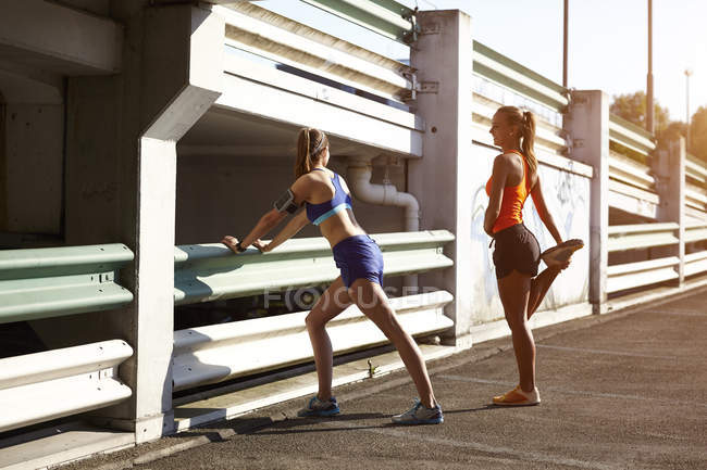 Dos jóvenes corredoras calentándose en el estacionamiento - foto de stock
