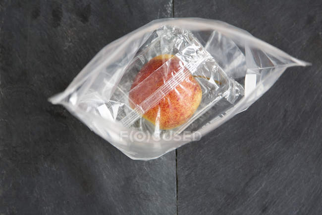 Vista superior de manzana envuelta en bolsas de plástico - foto de stock