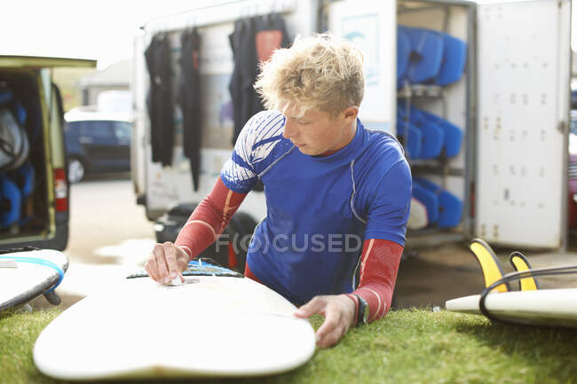 Male surfer waxing surfboard — Stock Photo