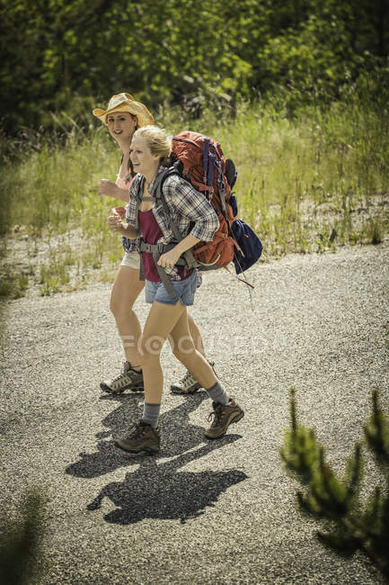 Junge Frau und Teenager-Mädchen wandern auf Landstraße, rote Hütte, Montana, USA — Stockfoto