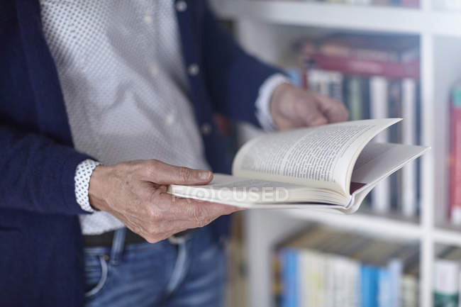 Abgeschnittene Aufnahme einer Frau, die Buch aus Bücherregalen liest — Stockfoto