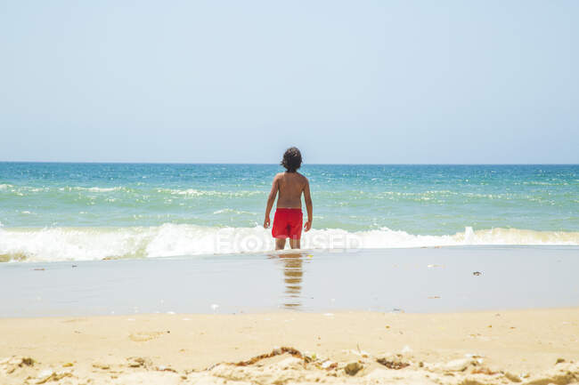 Visão traseira do menino no mar olhando para o horizonte, Cádiz, Espanha — Fotografia de Stock