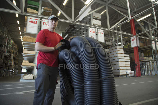 Portrait of worker with rolled up piping in hardware store warehouse — Stock Photo