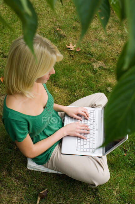 Fille sur ordinateur dans le jardin — Photo de stock