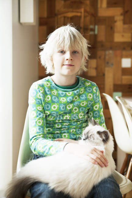 Portrait de garçon avec chat sur les genoux dans la cuisine — Photo de stock