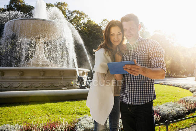 Casal usando tablet digital no parque — Fotografia de Stock