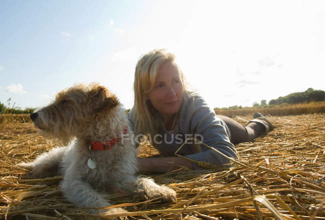 Женщина и Джек Рассел терьер лежат на поле — стоковое фото