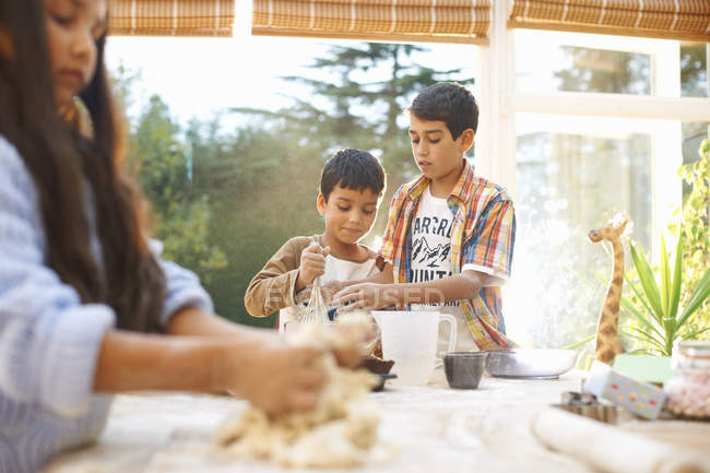 Дети делают тесто на кухне дома — стоковое фото