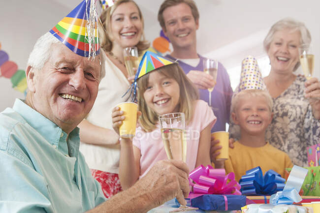 Mehrgenerationenfamilie blickt in Kamera und stößt lächelnd an — Stockfoto