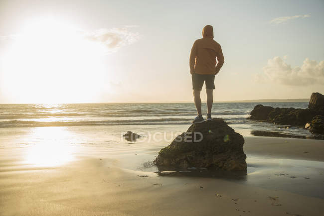 Reifer Mann, der auf einem Felsen steht und aufs Meer blickt — Stockfoto