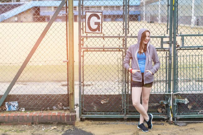 Young woman standing beside sports ground, London, UK — Stock Photo