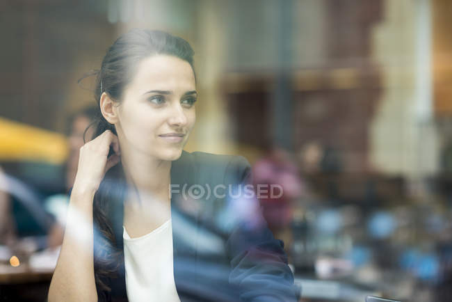 Giovane donna d'affari che guarda fuori dalla finestra del caffè, Londra, Regno Unito — Foto stock